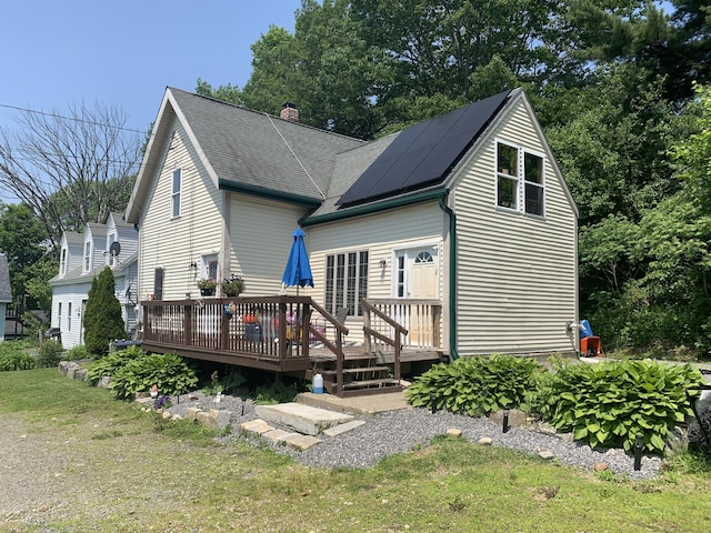 46 Windsor St, Randolph, ME 04346 - rear view of property with a chimney, a wooden deck, roof mounted solar panels, a lawn, and roof with shingles