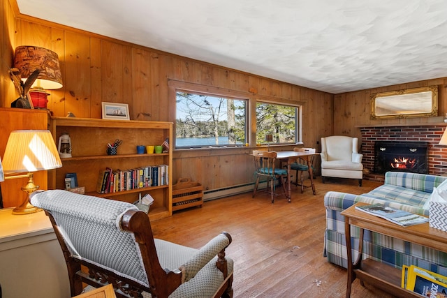 57 Samoset Trl, Boothbay, ME 04544 - living area featuring a baseboard heating unit, a brick fireplace, wood finished floors, and wooden walls