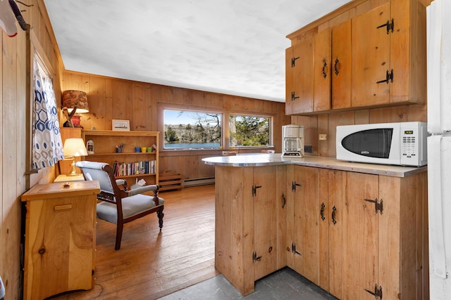 57 Samoset Trl, Boothbay, ME 04544 - kitchen with a baseboard radiator, light wood-style floors, wooden walls, white microwave, and a peninsula