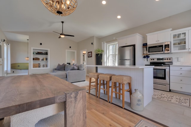 kitchen with a kitchen bar, white cabinetry, a kitchen island, light countertops, and stainless steel appliances