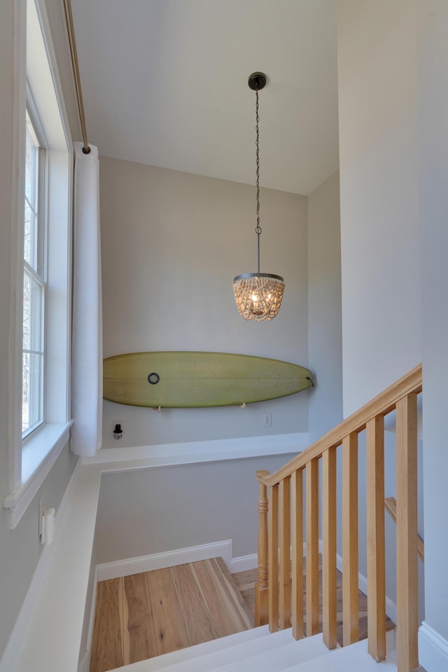 stairs with an inviting chandelier and wood finished floors