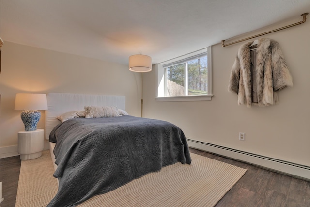 bedroom featuring wood finished floors and a baseboard heating unit