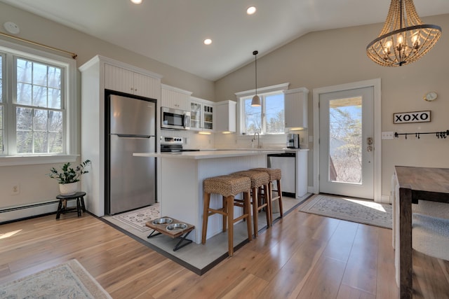 kitchen featuring a kitchen bar, white cabinetry, a kitchen island, appliances with stainless steel finishes, and lofted ceiling