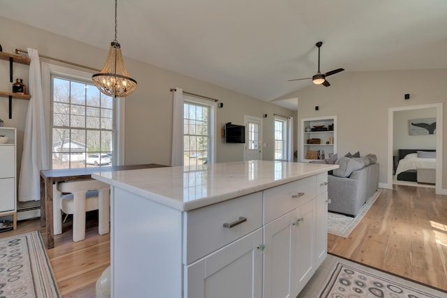 kitchen featuring light wood-type flooring, ceiling fan with notable chandelier, white cabinetry, and lofted ceiling