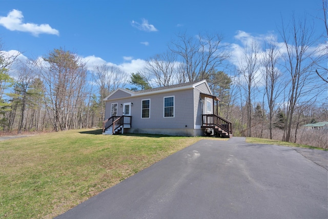 manufactured / mobile home with aphalt driveway and a front yard