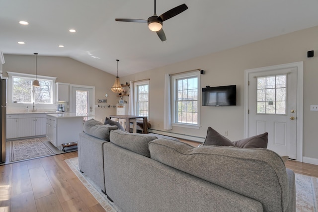 living room featuring baseboard heating, light wood-style flooring, and a wealth of natural light