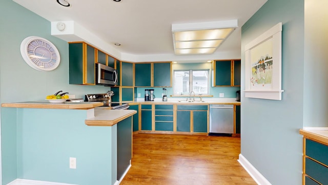 19 Spruce Head Rd, South Thomaston, ME 04858 - kitchen featuring appliances with stainless steel finishes, a sink, a peninsula, light wood finished floors, and light countertops