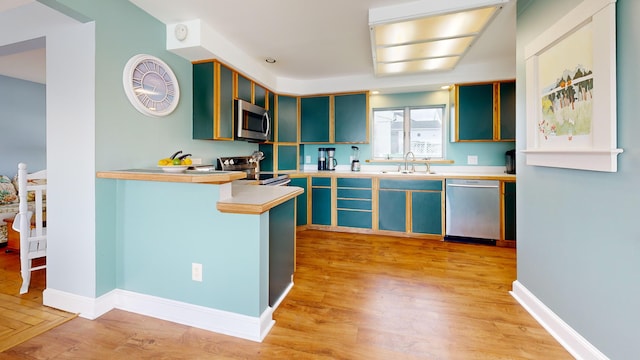 19 Spruce Head Rd, South Thomaston, ME 04858 - kitchen featuring appliances with stainless steel finishes, a sink, light wood-style floors, light countertops, and glass insert cabinets