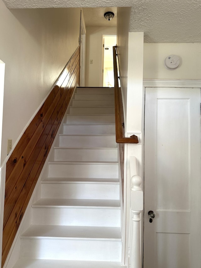 staircase featuring a textured ceiling