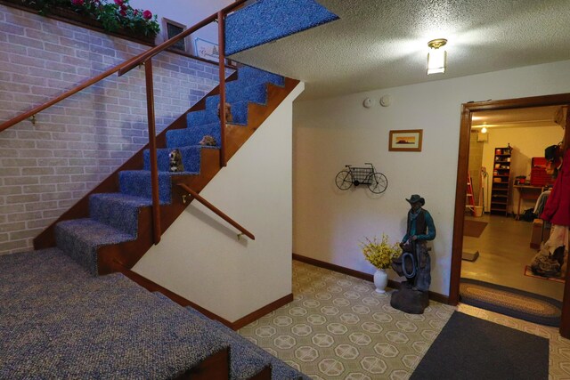 stairway with a textured ceiling, baseboards, and carpet floors