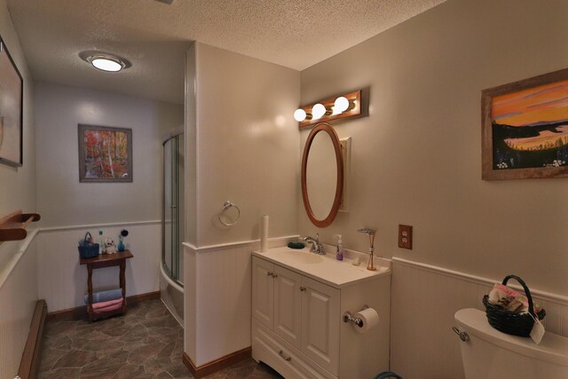 bathroom featuring vanity, toilet, wainscoting, and a textured ceiling