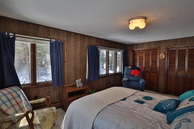 bedroom with wooden walls, a baseboard radiator, and a textured ceiling