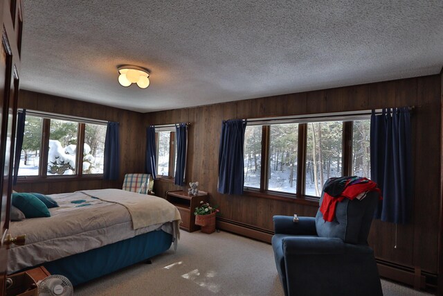 carpeted bedroom with a baseboard radiator, wood walls, and a textured ceiling