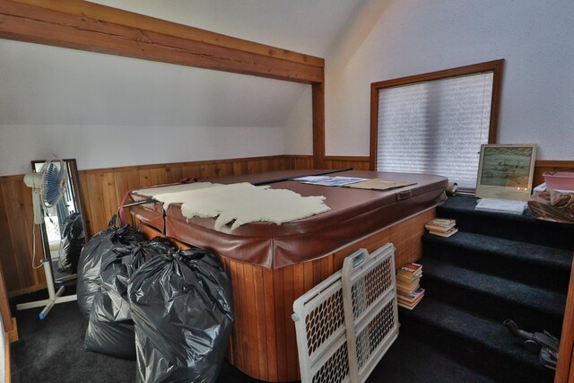 carpeted bedroom with vaulted ceiling with beams, wood walls, and wainscoting