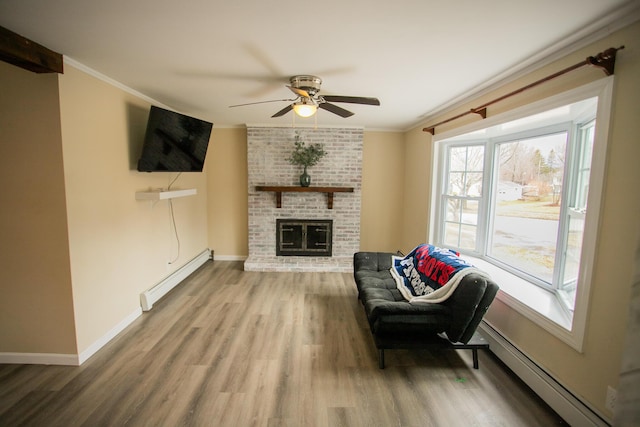 living area with ornamental molding, a baseboard radiator, ceiling fan, baseboard heating, and wood finished floors