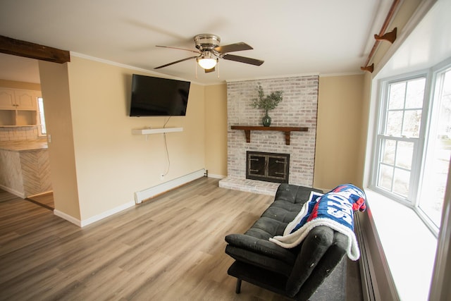 living room with baseboard heating, baseboards, ornamental molding, ceiling fan, and wood finished floors