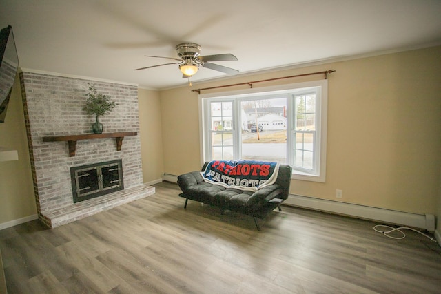 living area featuring baseboard heating, wood finished floors, and ceiling fan