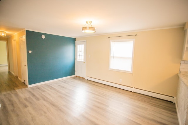 empty room featuring ornamental molding, a baseboard radiator, and wood finished floors