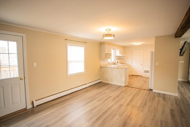 kitchen featuring a peninsula, baseboard heating, light countertops, and light wood-style flooring