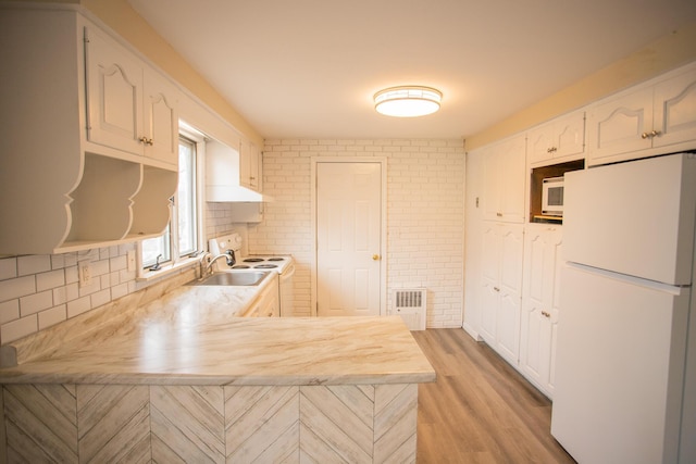 kitchen featuring white appliances, light wood-style floors, light countertops, and a peninsula