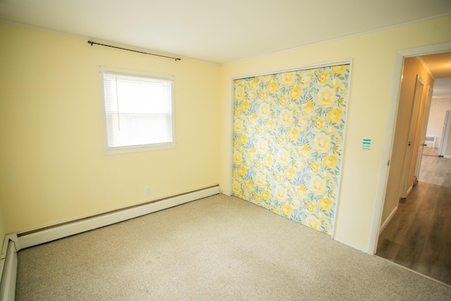 carpeted spare room featuring baseboard heating