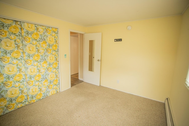 spare room with carpet and a baseboard heating unit