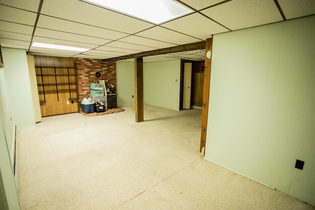 finished below grade area with wood walls, a drop ceiling, and carpet floors