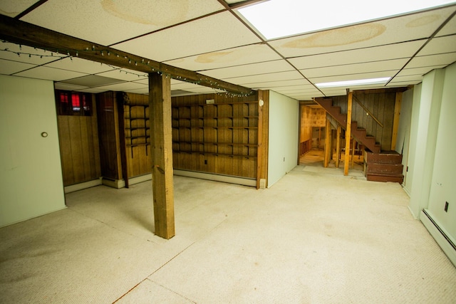 finished below grade area featuring a baseboard radiator, stairway, and a paneled ceiling
