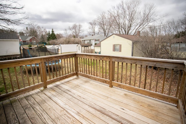 wooden deck with a trampoline, a residential view, an outbuilding, and a storage unit