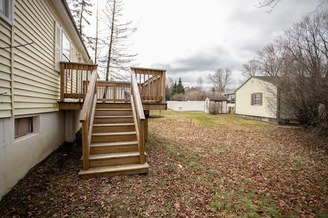 view of yard with fence, a deck, and stairs