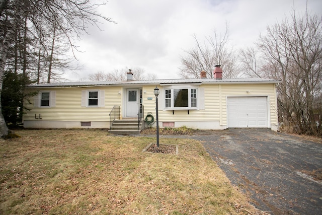 ranch-style house with aphalt driveway, metal roof, a chimney, and an attached garage