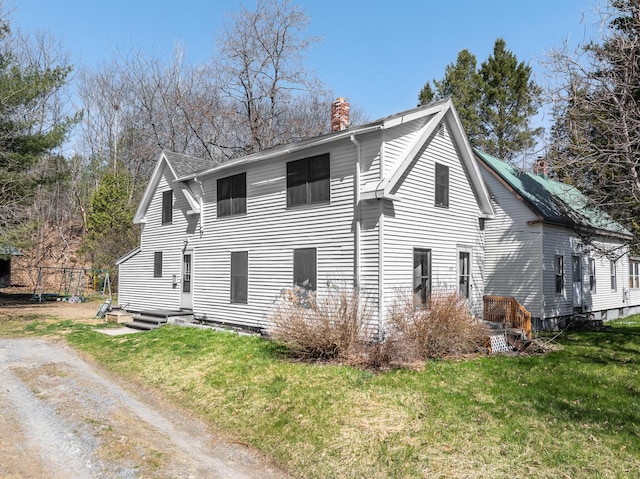 view of side of property featuring a lawn, a chimney, and driveway
