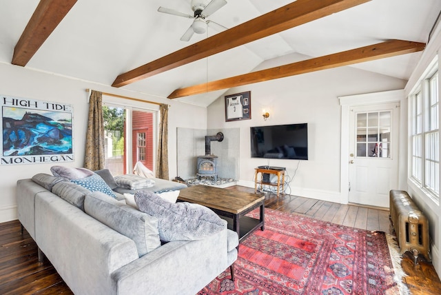living room with lofted ceiling with beams, a wood stove, radiator, baseboards, and dark wood-type flooring