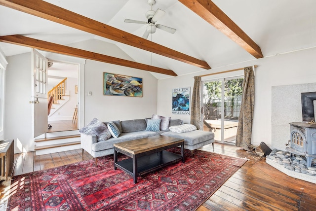 living room with a wood stove, vaulted ceiling with beams, hardwood / wood-style flooring, and a ceiling fan