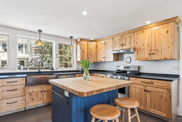 kitchen with a sink, light brown cabinets, under cabinet range hood, wooden counters, and stainless steel gas range oven
