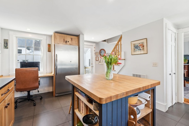 kitchen featuring stainless steel fridge, visible vents, open shelves, dark tile patterned floors, and wooden counters