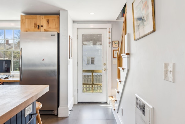 doorway to outside with stairs, heating unit, dark tile patterned flooring, and baseboards