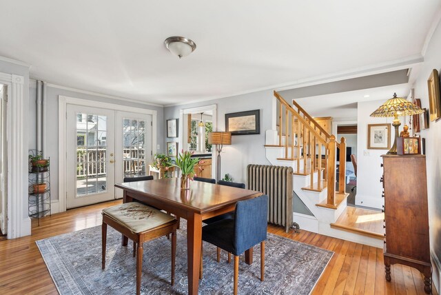 dining area featuring radiator heating unit, stairway, light wood finished floors, french doors, and crown molding