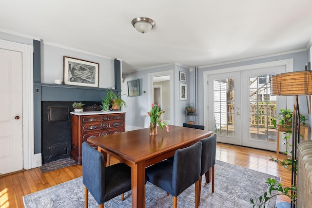 dining room featuring french doors, light wood-style floors, and crown molding