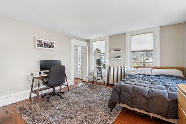 bedroom with baseboards, radiator heating unit, and wood finished floors
