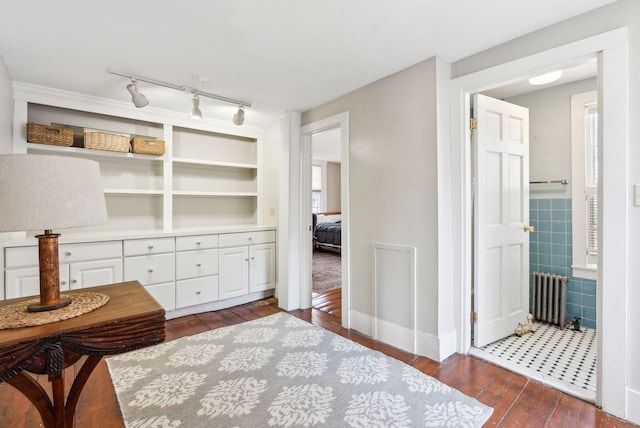 sitting room featuring track lighting, radiator heating unit, dark wood-type flooring, and tile walls
