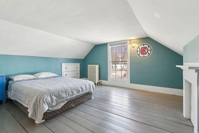 bedroom with wood-type flooring, vaulted ceiling, and radiator