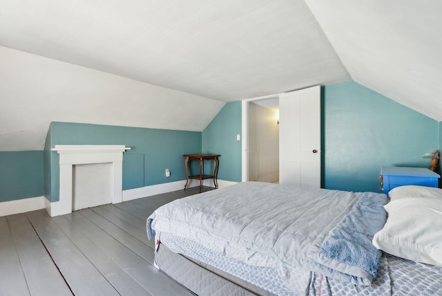bedroom with lofted ceiling, wood finished floors, and baseboards