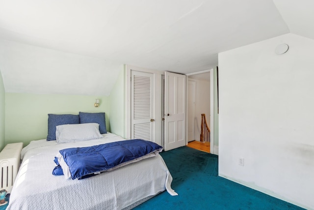 carpeted bedroom with radiator, vaulted ceiling, and a closet