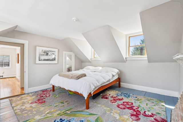 bedroom featuring baseboards, lofted ceiling, hardwood / wood-style flooring, and multiple windows