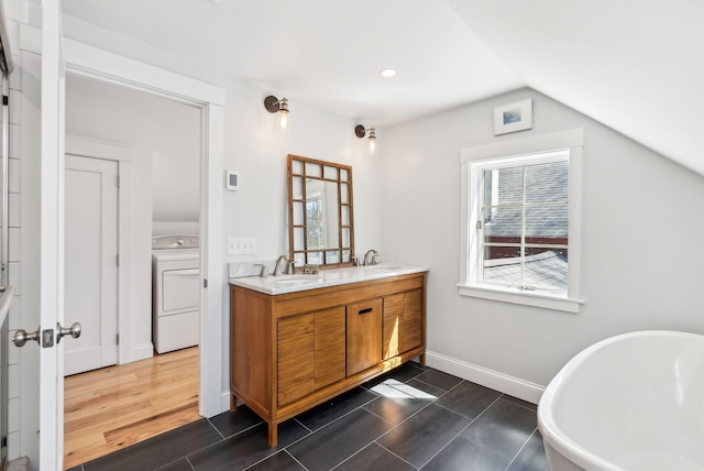 full bathroom featuring washer / dryer, a soaking tub, a sink, and plenty of natural light