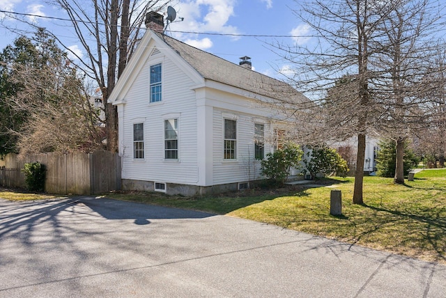 view of side of property with a chimney, fence, and a yard