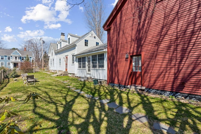 view of property exterior with a lawn, fence, a residential view, and entry steps