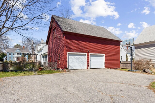 garage with aphalt driveway and fence