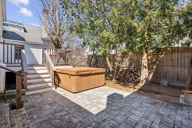 view of patio featuring stairs, a hot tub, a fenced backyard, and a deck
